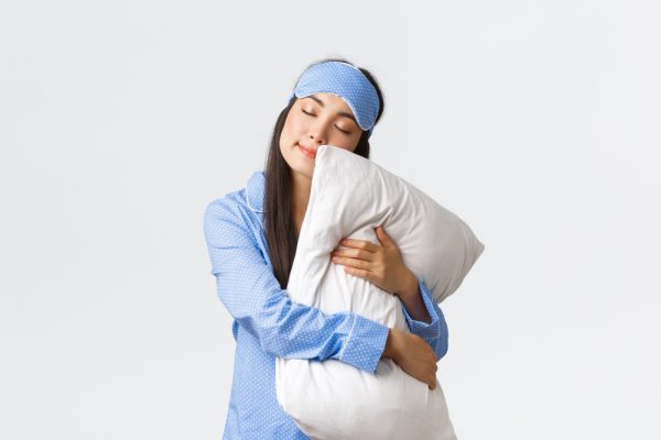 charming-sleeping-asian-girl-in-eyemask-and-pyjama-hugging-pillow-and-lying-on-it-with-closed-eyes-dreaming-having-night-sleep-posing-over-white-background-dreamy-copy-space